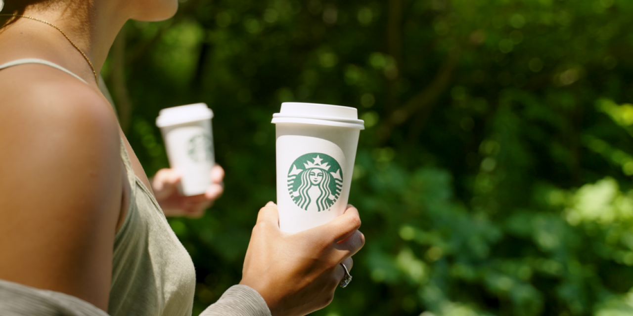 A woman holds up a Starbucks™ hot drink